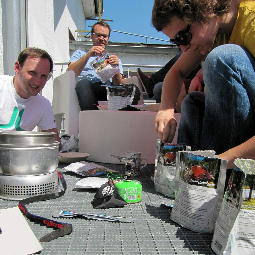 Personen sitzen auf einem Balkon und testen Trekkingnahrung