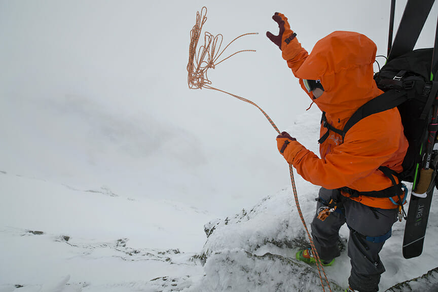 Person mit orangenen Handschuhen klettert im Schnee